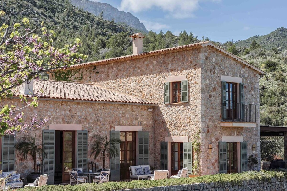A large stone house with green shutters on the windows