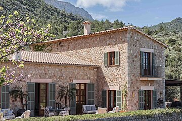 A large stone house with green shutters on the windows