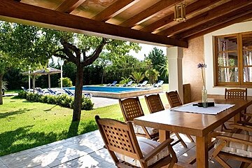 A table and chairs on a patio with a pool in the background