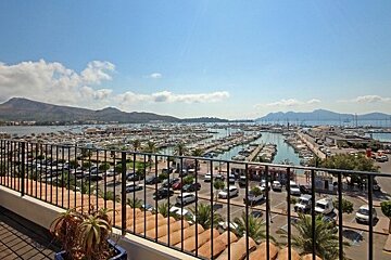 A view of a marina from a balcony with mountains in the background