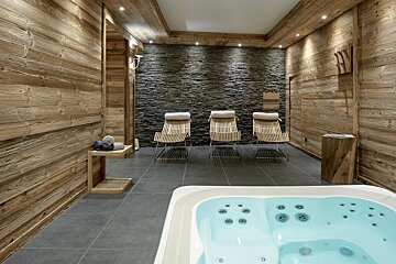 A hot tub in a room with wooden chairs