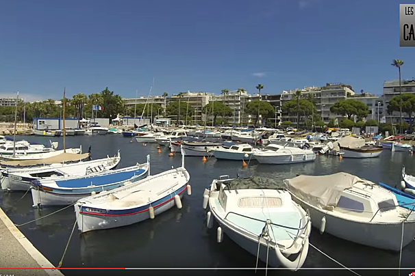 Boats are docked in a harbor with a sign that says les rues de cannes