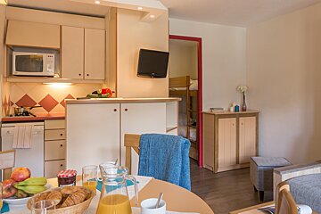 A kitchen with a microwave and a tv on the wall