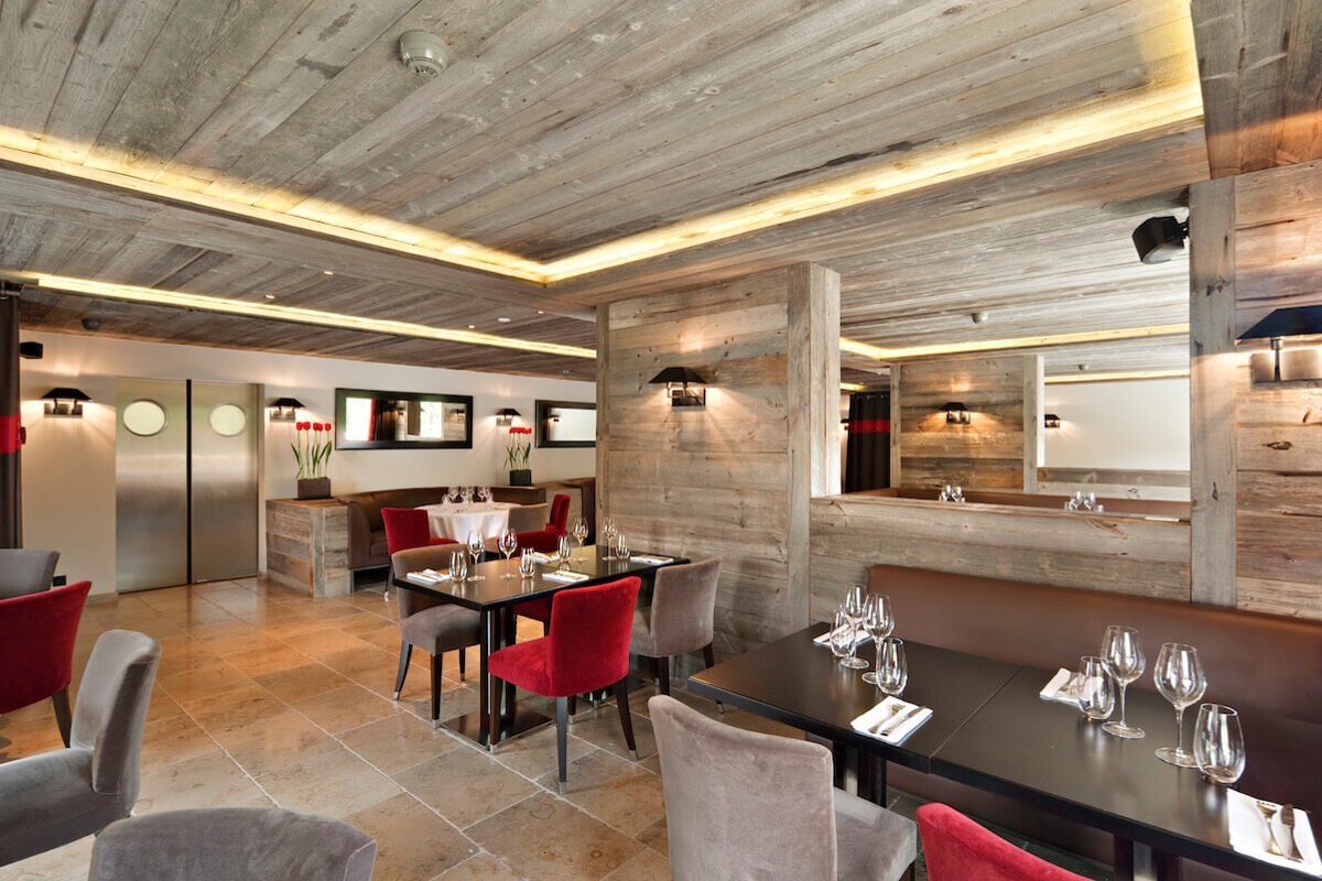 A dining room with tables and chairs and a stainless steel refrigerator