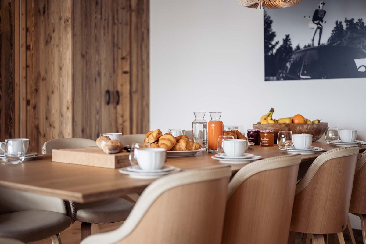 A table with a tray of croissants and a bottle of orange juice