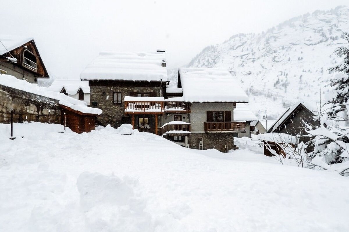 A snowy landscape with a few houses covered in snow