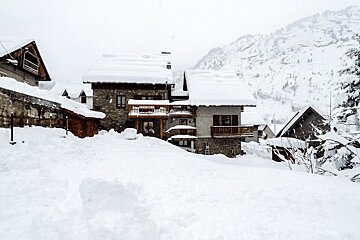 A snowy landscape with a few houses covered in snow