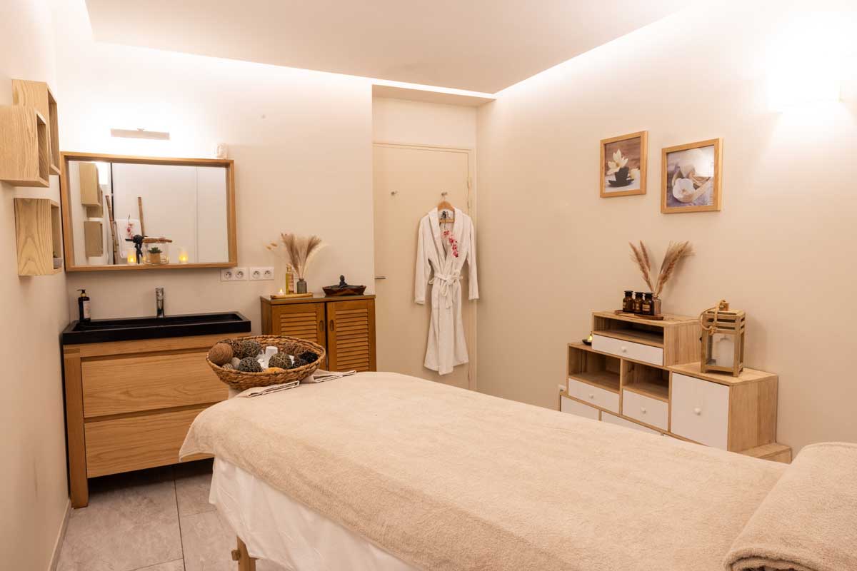 A massage table in a room with a bathrobe hanging on the wall