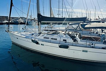 A white sailboat is docked in a harbor and has the letters nm on the side