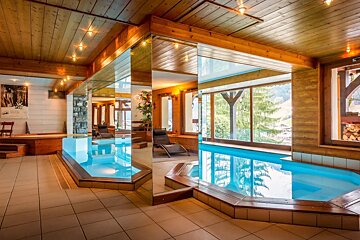 A large indoor swimming pool is surrounded by mirrors