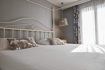 A bedroom with a canopy bed and a lamp hanging from the ceiling