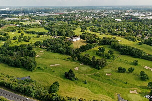 An aerial view of a golf course with a castle in the distance
