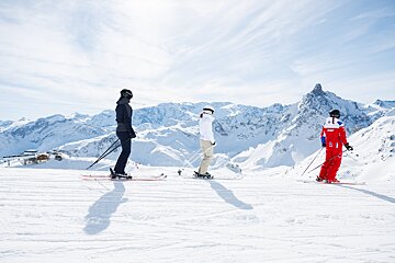 Skiers on a snowy slope with one wearing a red jacket with the number 8 on it