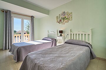 A bedroom with two beds and a painting on the wall