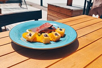 A blue plate of food with meat and potatoes on a wooden table