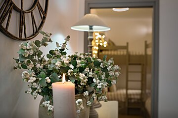 A vase of white flowers sits next to a lit candle