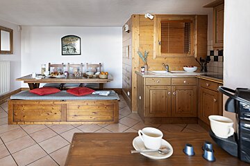 A kitchen with wooden cabinets and a table with red pillows