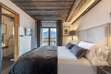 A bedroom with a king size bed and a tv on the wall