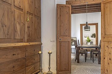 A wooden door open to a dining room with a table and chairs