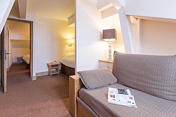 A couch in a hotel room with a magazine on it