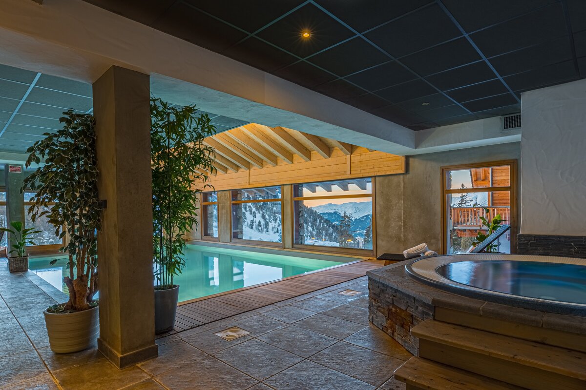 A large indoor swimming pool with a hot tub next to it