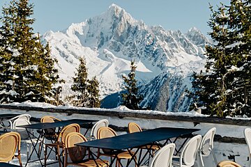 Tables and chairs in front of a snowy mountain