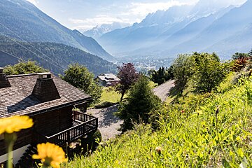 A mountain landscape with a house in the foreground