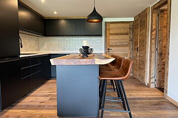 A kitchen with black cabinets and a wooden counter top