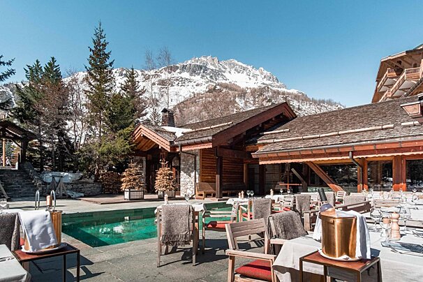A restaurant with a pool and a mountain in the background