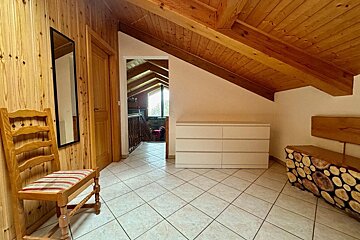 A white dresser sits in a hallway next to a chair and a mirror