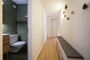 A hallway with hooks on the wall and a toilet
