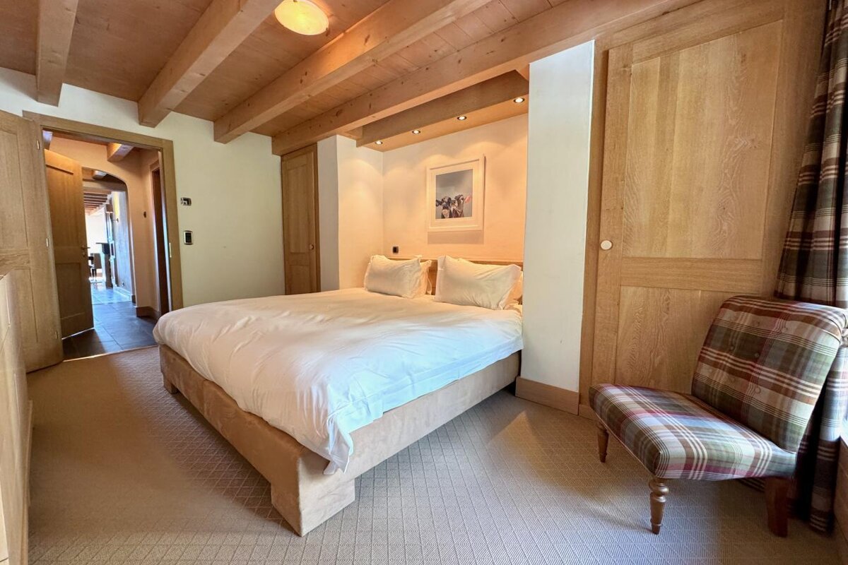 A bedroom with a large bed and a chair