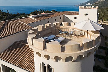 An aerial view of a castle with a balcony overlooking the ocean