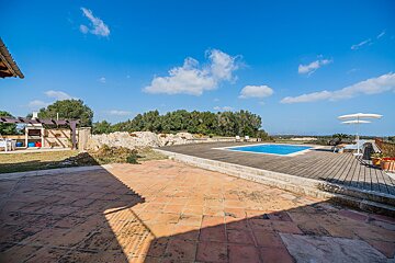 A large swimming pool is surrounded by a wooden deck