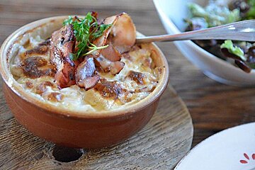 A bowl of food with bacon and a spoon in it