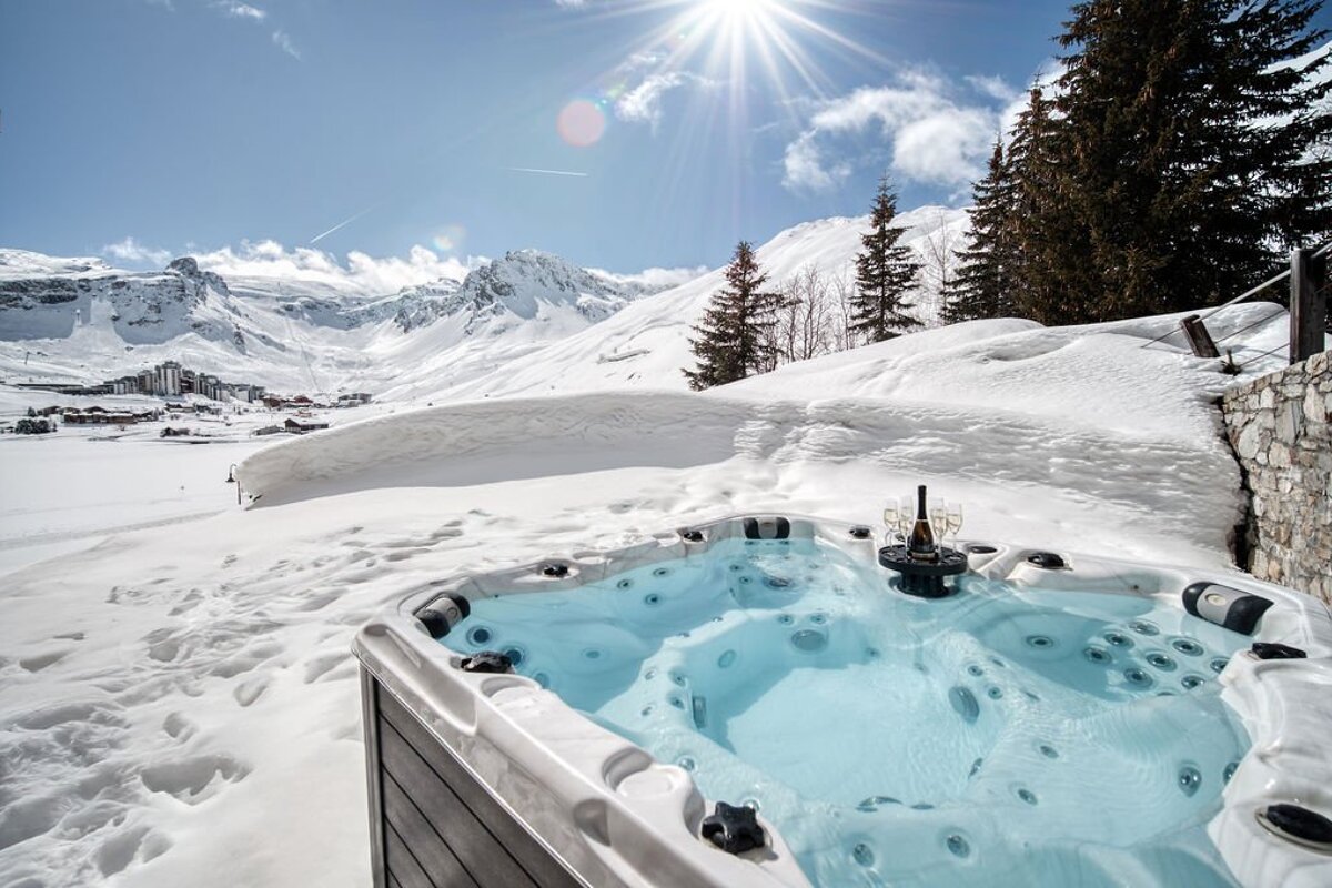 A hot tub in the snow with mountains in the background