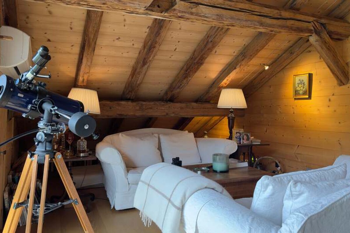 A living room with a telescope and a couch