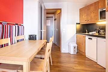 A kitchen with a table and chairs and a trash can