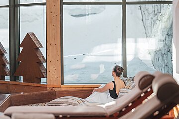 A woman sits on a couch looking out a window