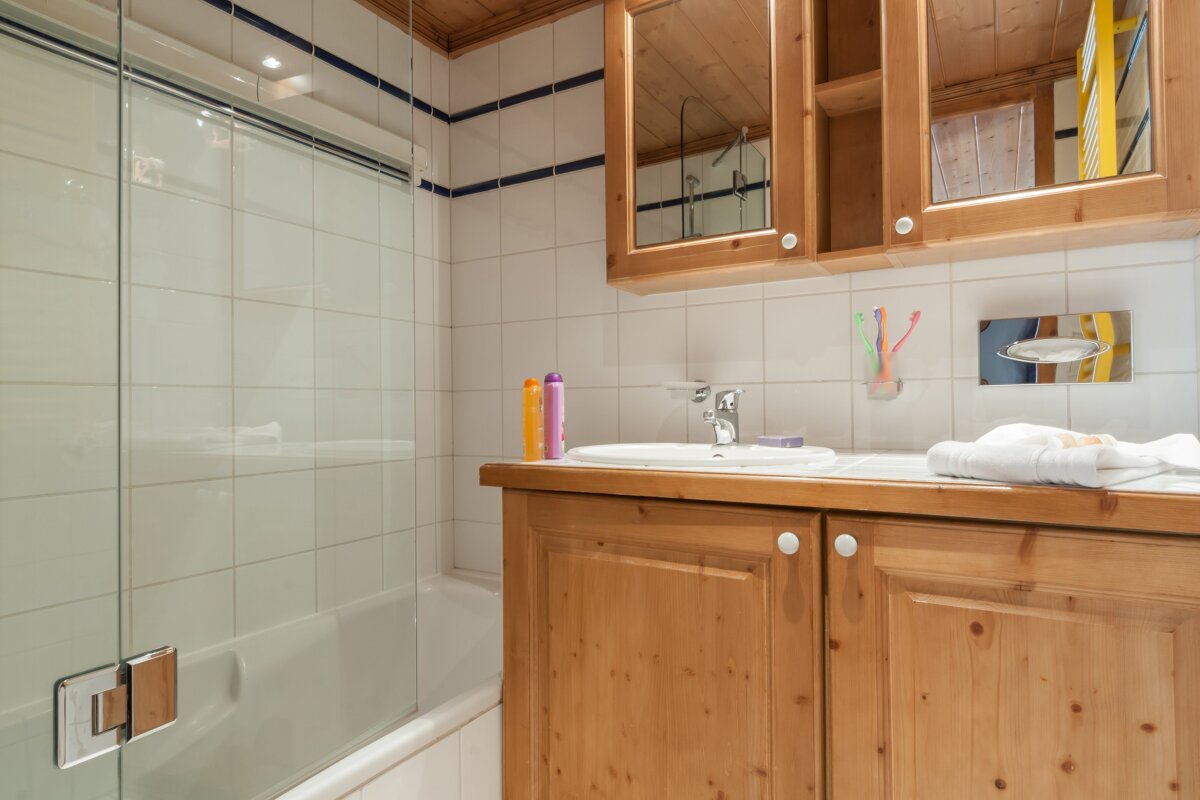 A bathroom with wooden cabinets and a glass shower door
