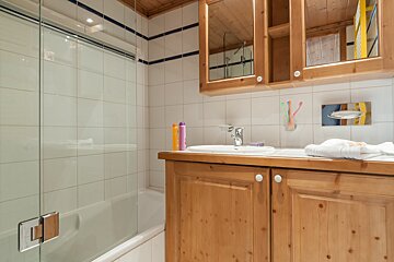 A bathroom with wooden cabinets and a glass shower door
