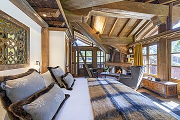 A bedroom with a bed a chair and a fireplace
