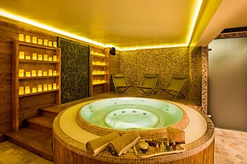 A jacuzzi in a room with candles on the shelves