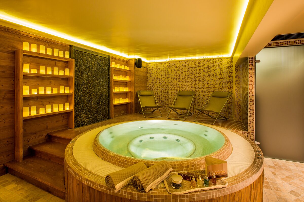 A jacuzzi in a room with candles on the shelves