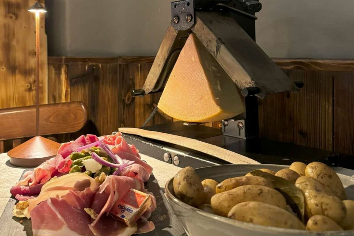 A slice of cheese is being cut in a machine next to a bowl of potatoes