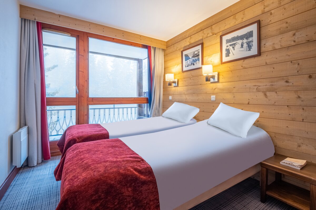A hotel room with two beds and two pictures on the wall