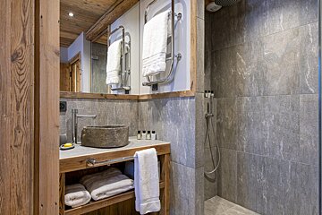 A bathroom with a stone sink and a walk in shower