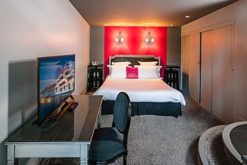 A hotel room with a bed a desk and a flat screen tv