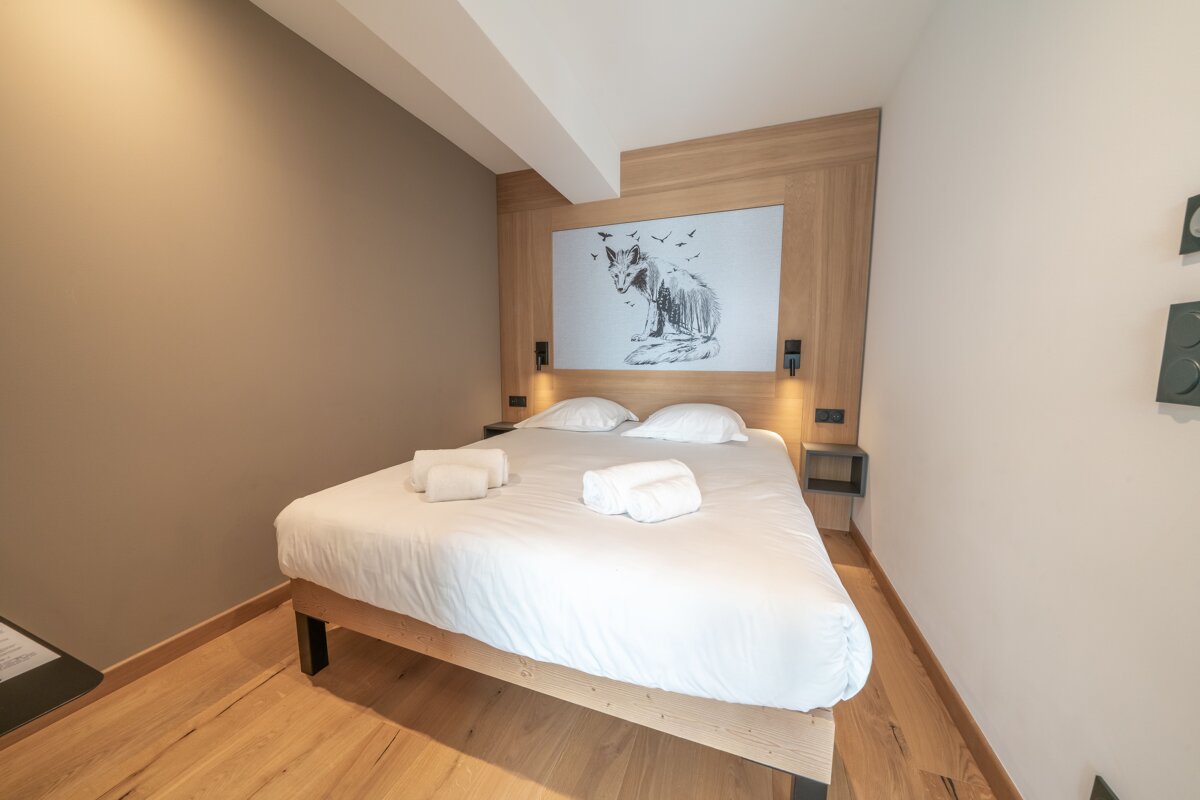 A bedroom with a bed and a painting of a fox on the wall