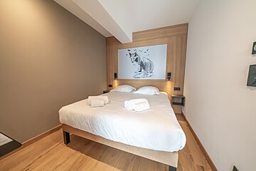 A bedroom with a bed and a painting of a fox on the wall